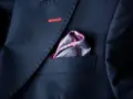 Elegancka poszetka w paisley do granatowego garnituru, z subtelnym czerwonym przeszyciem na klapie.