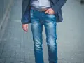 Mężczyzna w eleganckiej marynarce i modnych, przetartych jeansach. Różne rodzaje spodni, od eleganckich po casualowe, pozwalają na tworzenie unikalnych stylizacji.