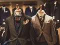 Eleganckie męskie garnitury w różnych kolorach i wzorach, prezentowane na manekinach. W tle widać więcej stylizacji.