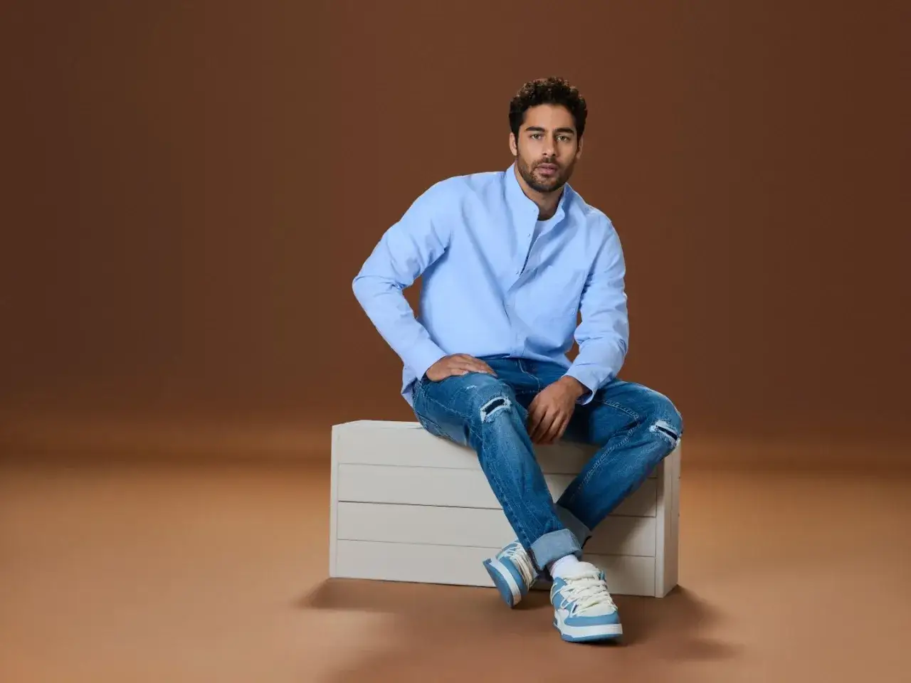 Mężczyzna w niebieskiej koszuli i podartych jeansach tworzy stylowy jeans total look.
